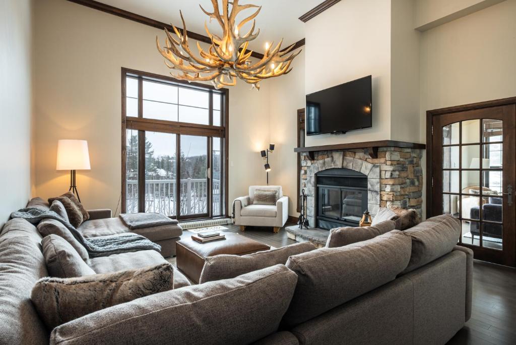 a living room with a large couch and a fireplace at BONDURANT 95-15 / Luxury 3 bdr on the village in Mont-Tremblant