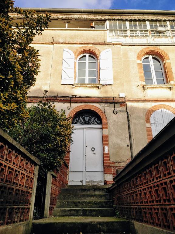 un bâtiment avec une porte blanche et des escaliers à l'avant. dans l'établissement Ici c'est Cosy - Centre, à Toulouse