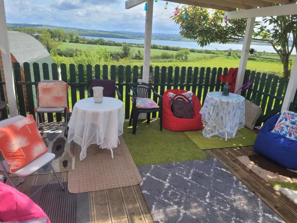 a patio with a table and chairs and a fence at Shannon Estuary Glamping in Effernan