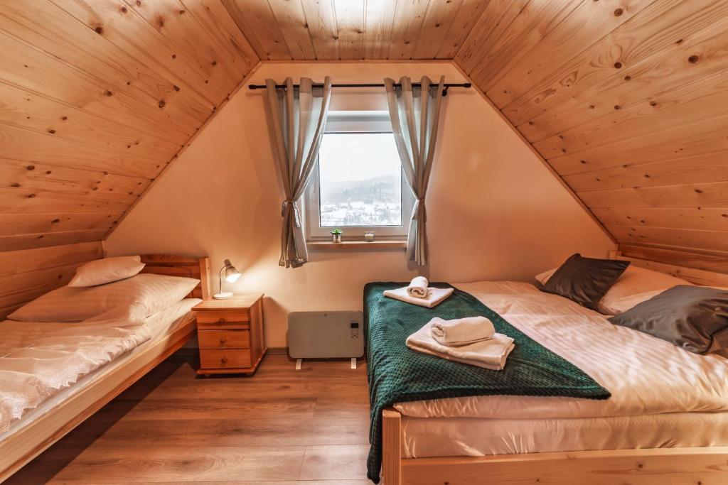 - une chambre avec 2 lits et une fenêtre dans l'établissement Domki Wichrowe Wzgórze, à Wisła