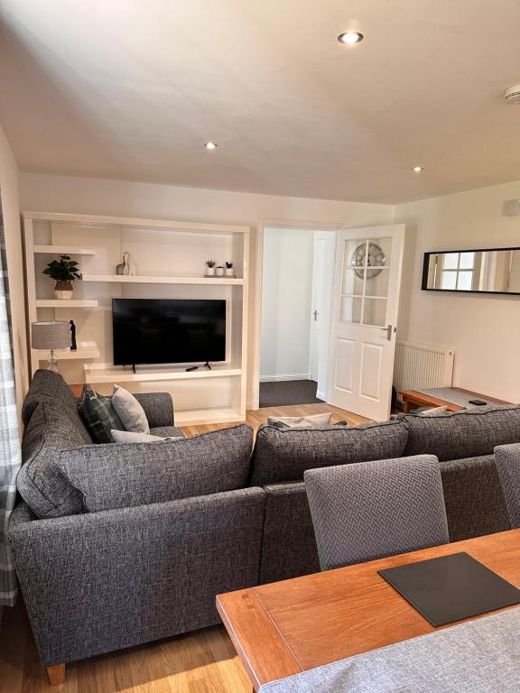 a living room with a couch and a television at Apartment in Queens Court, Banchory in Inchmarlo