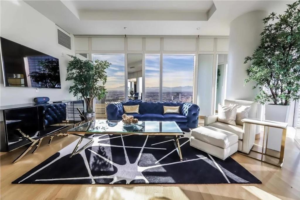 a living room with a blue couch and a table at Elegant Corner 2 Bedroom Condo with Floor to Ceiling Windows in Las Vegas