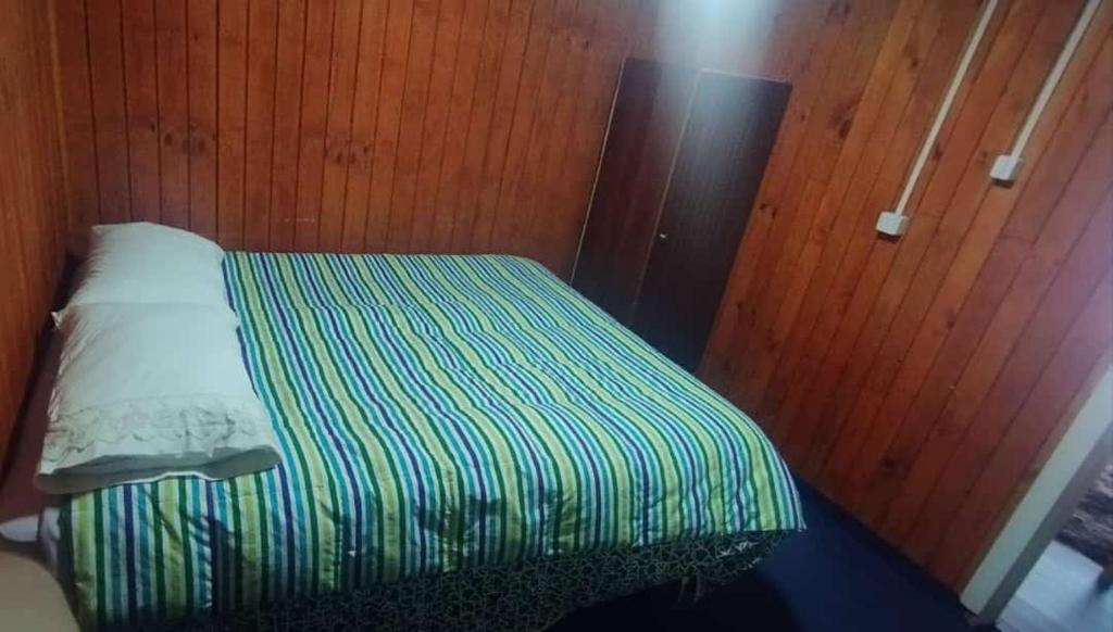 a small bed in a room with wooden walls at Departamento céntrico quellón in Quellón
