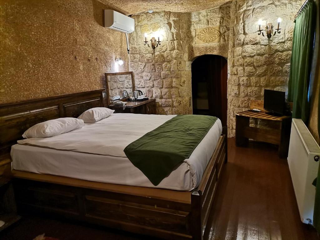 a bedroom with a large bed in a room with stone walls at CAPPADOCIA PALACE HOTEL in Nevşehir