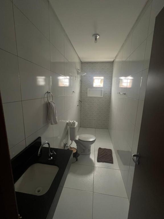 a white bathroom with a sink and a toilet at Quarto em casa compartilhada in Petrolina