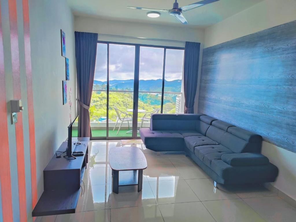 キャメロンハイランドにあるCooling Point Homestay @ Palas Horizon Residenceの青いソファと大きな窓のあるリビングルーム