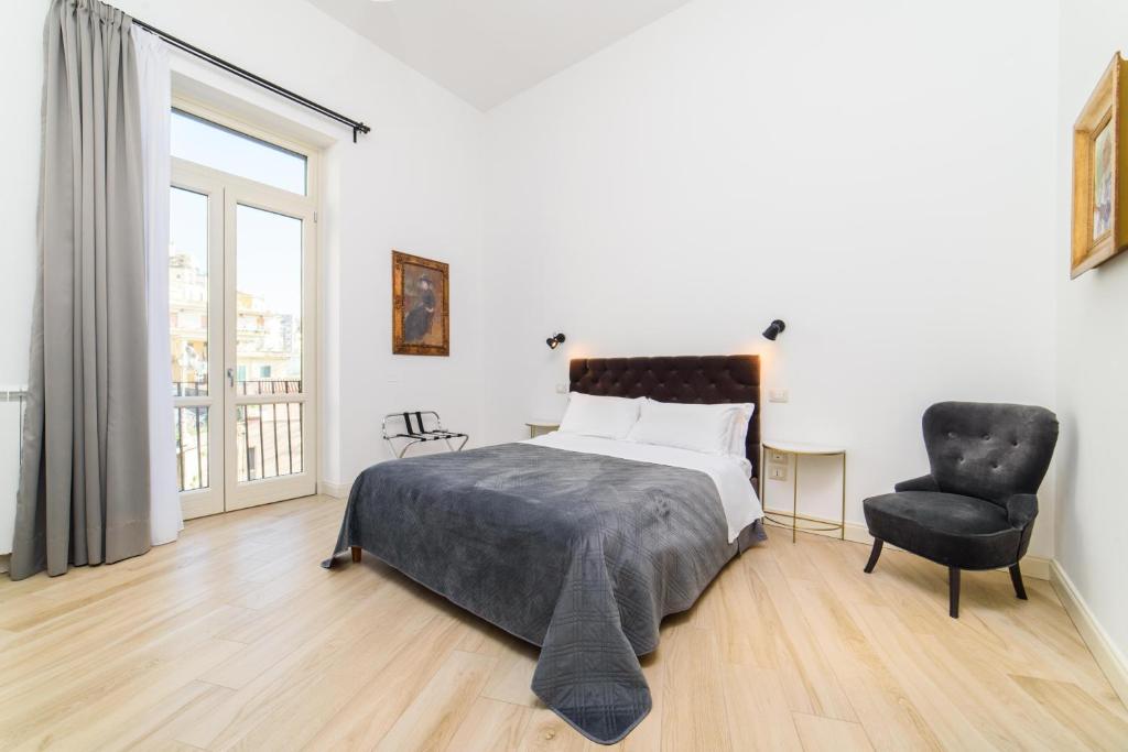 ein Schlafzimmer mit einem Bett, einem Stuhl und einem Fenster in der Unterkunft One&One in Salerno