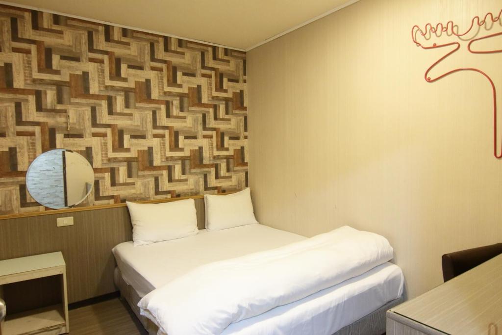 a room with two beds and a wall with a painting at Baoshan Hotel in Zhongli