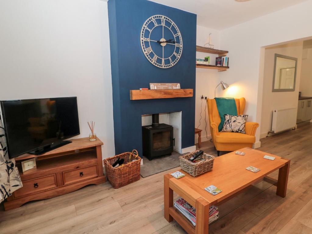 a living room with a fireplace and a clock on the wall at Myrtle Cottage in Morpeth