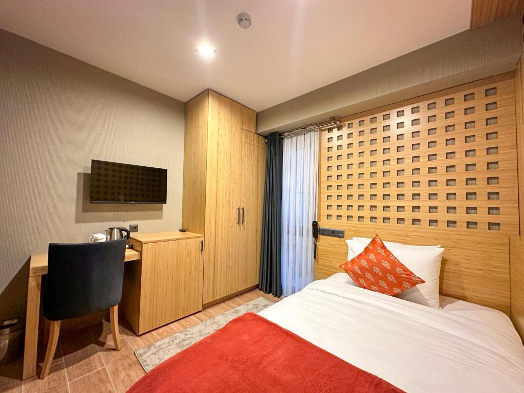 a bedroom with a bed and a desk and a television at Mihman Hotel in Tuzla