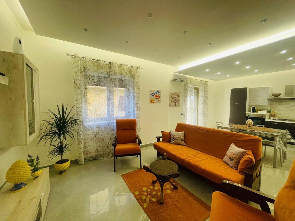 sala de estar con sofá naranja y mesa en La Pigna Casa Vacanza, en Nicolosi