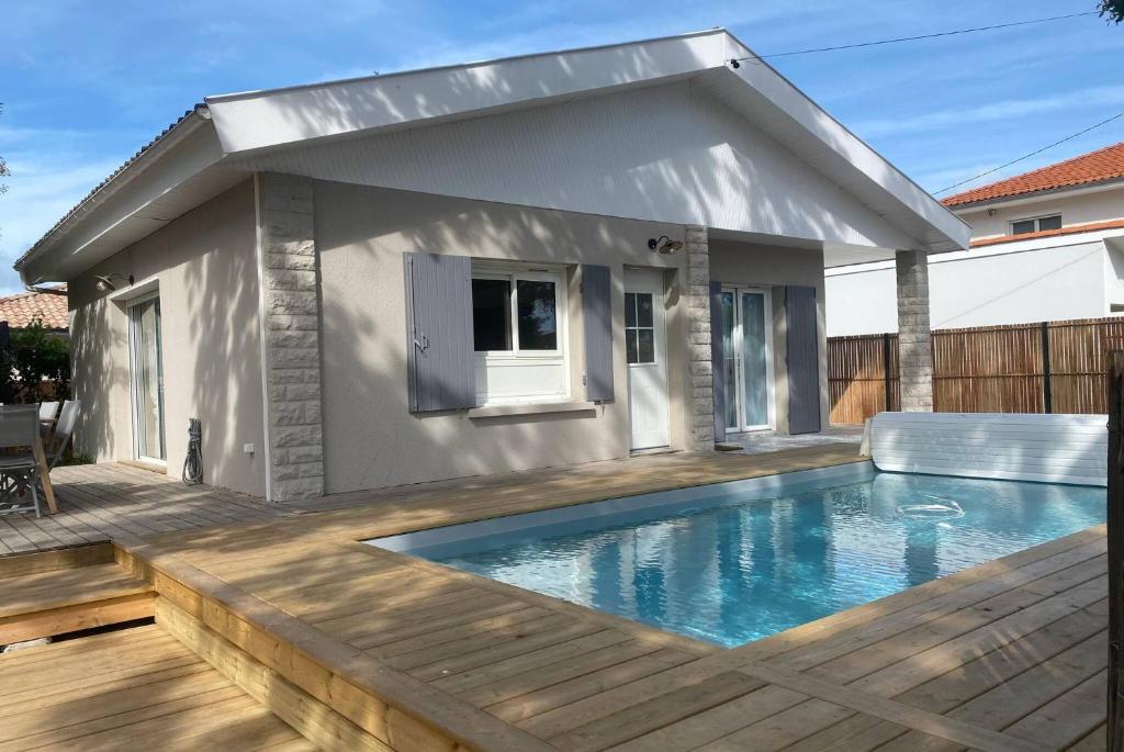 une piscine avec une terrasse et une maison dans l'établissement VILLA DES BECASSES - Andernos les Bains, à Andernos-les-Bains