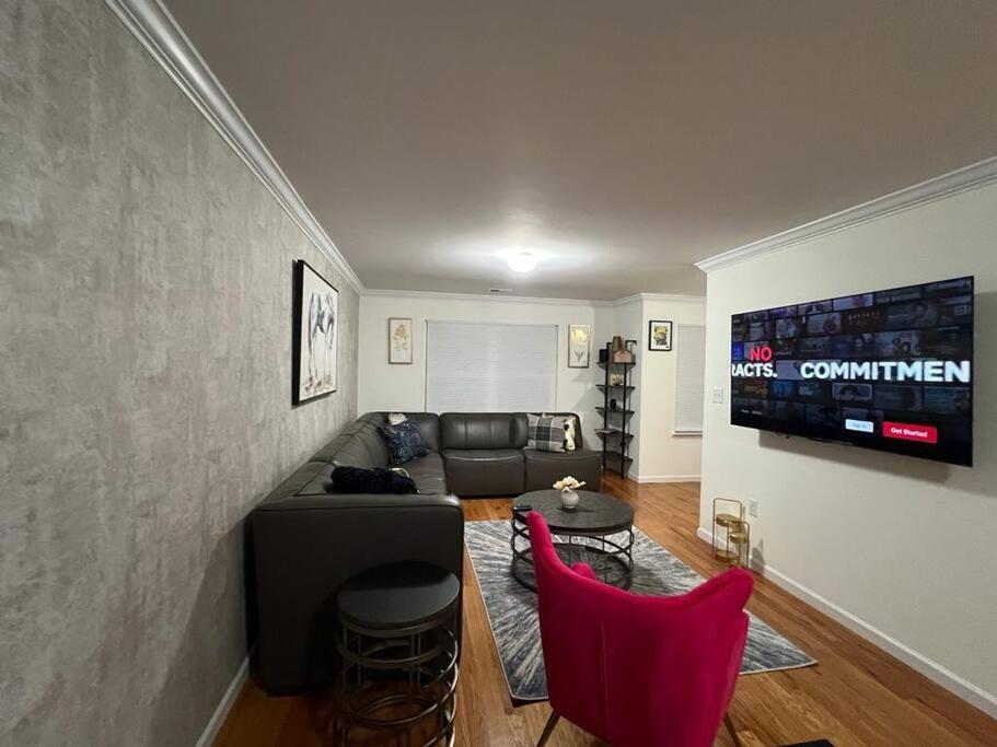 uma sala de estar com um sofá preto e cadeiras vermelhas em NEwark Airport Elegant 3 Kings APT em Elizabeth