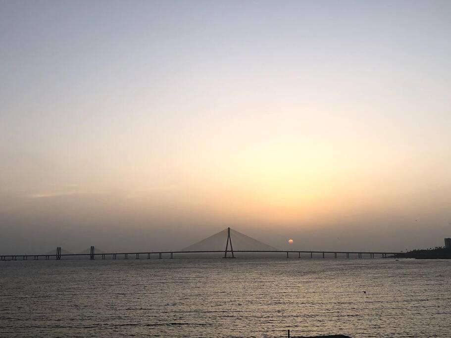a bridge over the water with the sunset in the background at Sealink view Apartment next to Hinduja Hospital in Mumbai