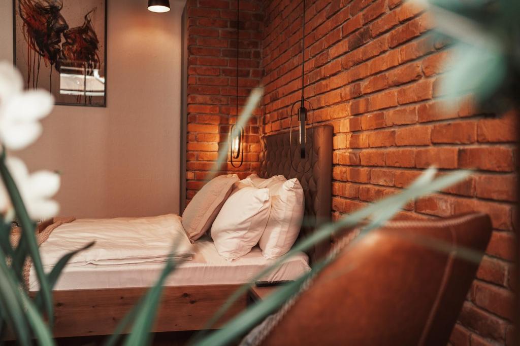 een bed in een kamer met een bakstenen muur bij Gentry11 Rooms&More in Maribor