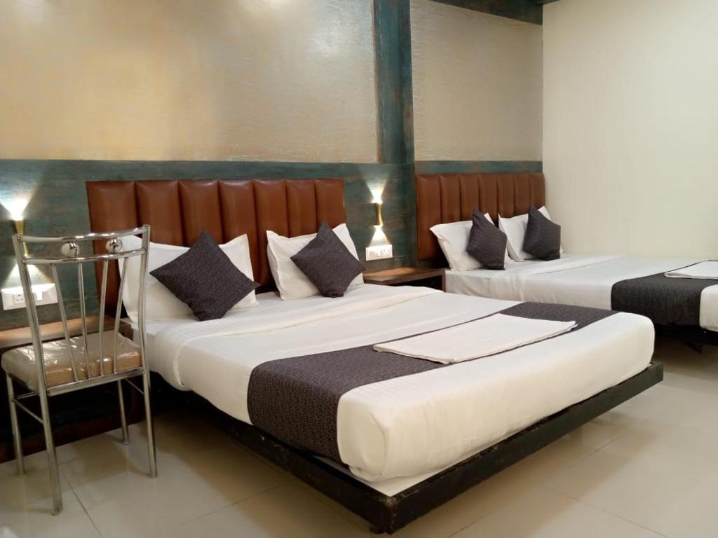 a bedroom with two beds and a chair at TRI HOTEL in Mumbai