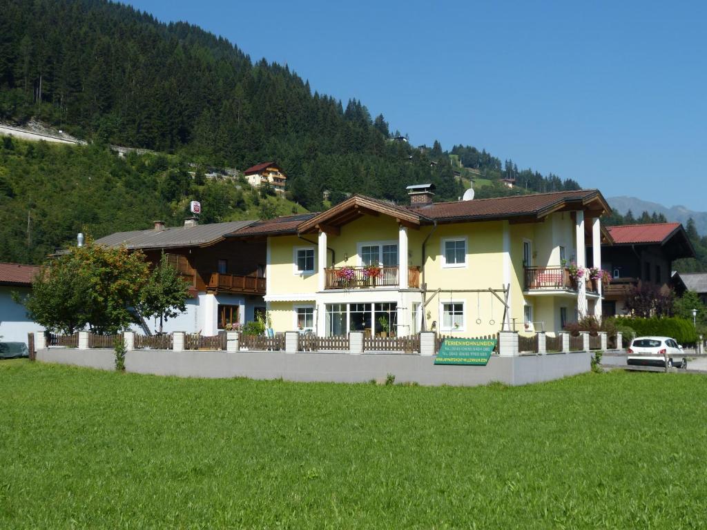 ein großes gelbes Haus auf einem Hügel mit einem grünen Feld in der Unterkunft Appartement Millennium in Bad Gastein
