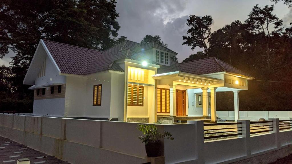 una casa blanca con una valla delante en Royal Home, en Kuravalangād