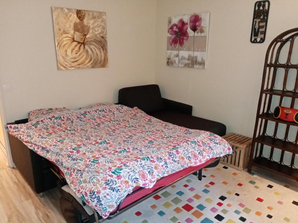 a bedroom with a quilt on a bed and a chair at Studio Cosy avec terrasse face au parc des expositions in Vanves