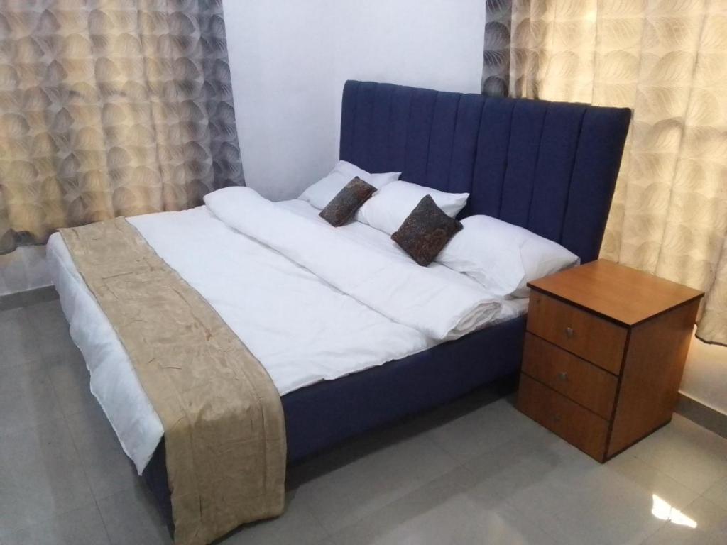 a blue bed with white sheets and pillows and a table at St Theresa apartment Lodge in Lagos
