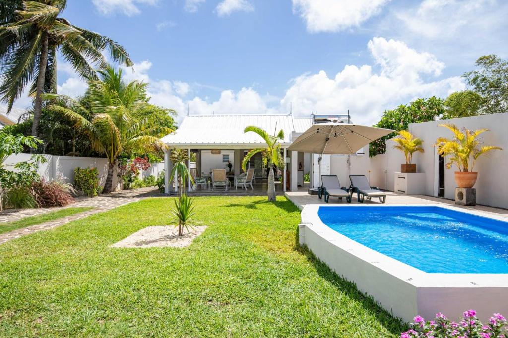 un patio trasero con piscina y una casa en Quaint 4BDR villa with pool in Grand Gaube en Grand Gaube