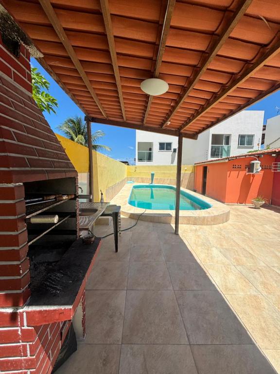 a patio with awning next to a swimming pool at Hostel e Pousada Jacumã in Conde