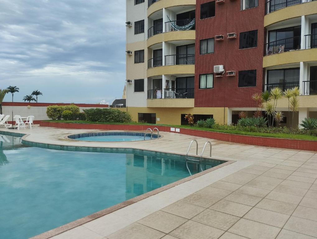 a swimming pool in front of a building at flats aconchegantes piscina e academia via park in Campos dos Goytacazes
