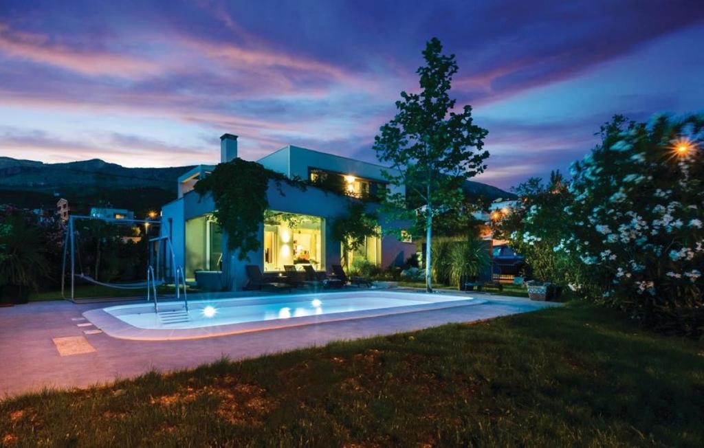 a house with a swimming pool at night at Villa Rasko with private heated pool in Podstrana