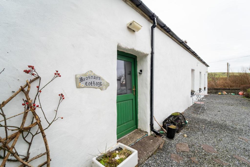 een wit gebouw met een groene deur bij Brosnan's Cottage in Dingle