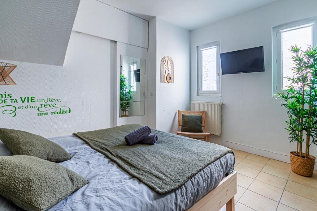 a bedroom with a bed and a tv on the wall at Appart'Hotel NuiteeJour Versailles Saint Cyr l'Ecole in Saint-Cyr-lʼÉcole