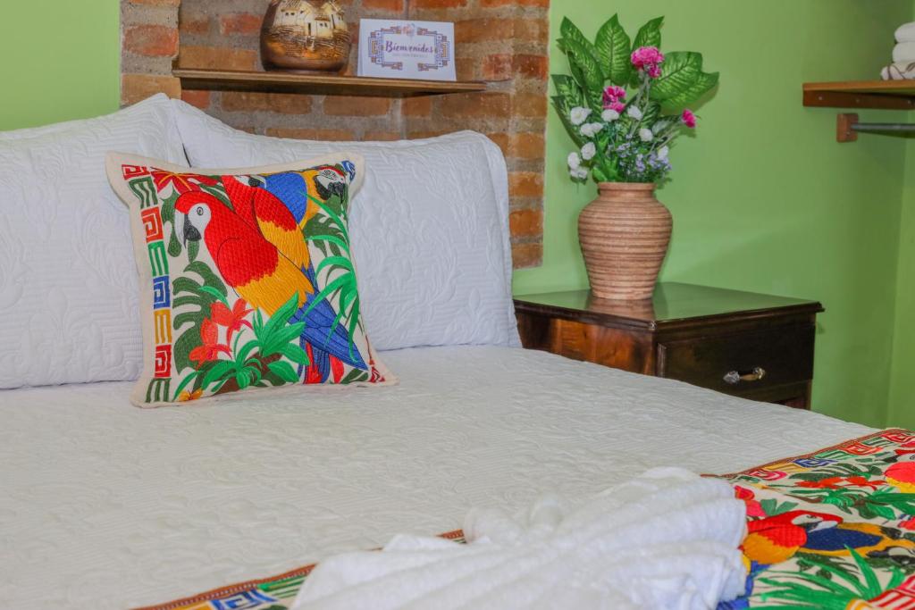 a bed with a pillow and a vase of flowers at Hotel Itzae in Copán Ruinas