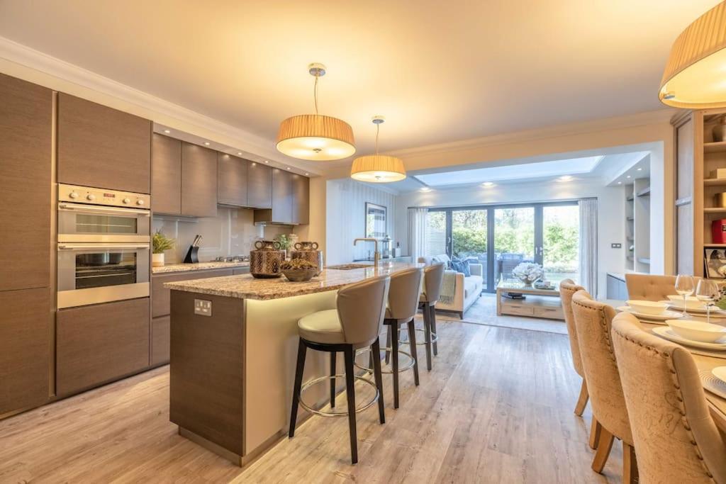 バージニア・ウォーターにあるElegant 4-Bed Home,Private Garden,Parkingのバースツール付きの大きな島のあるキッチンが備わります。