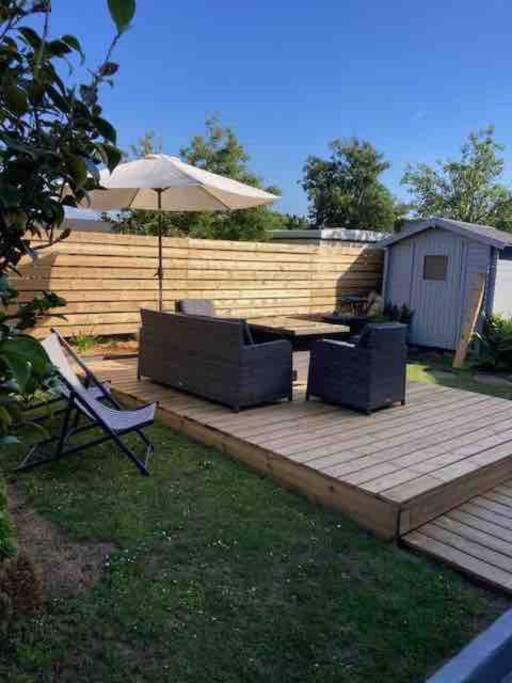 a wooden deck with an umbrella and two chairs and an umbrella at Ty glaz in Ploubazlanec
