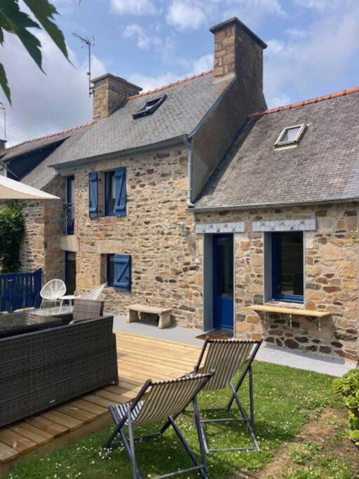 une maison en pierre avec 2 chaises sur une terrasse en bois dans l'établissement Ty glaz, à Ploubazlanec