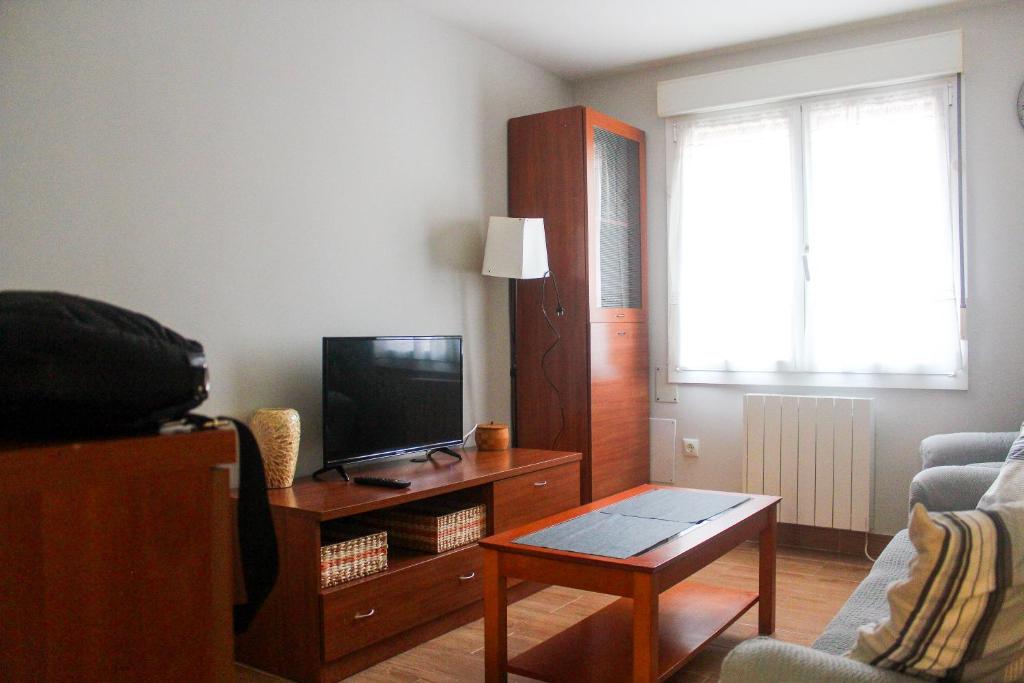 uma sala de estar com uma televisão numa mesa de madeira em Casa Gelina em Gijón