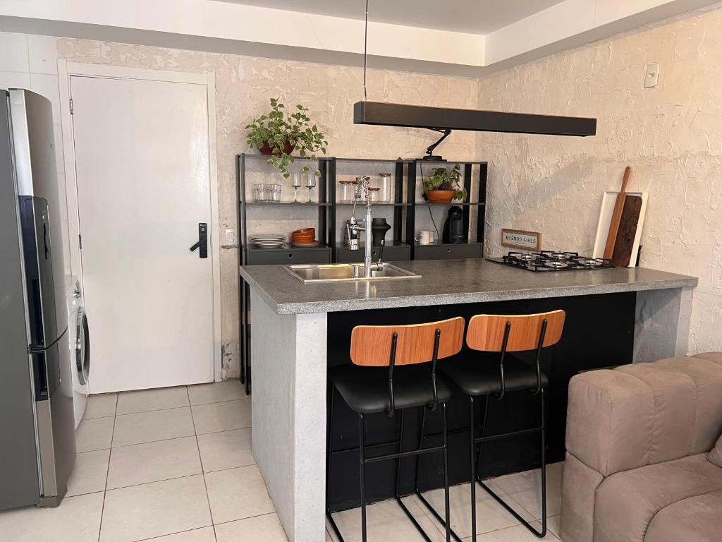 eine Küche mit einer Theke mit einer Spüle und 2 Barhockern in der Unterkunft Confortavel apartamento em SP in São Paulo