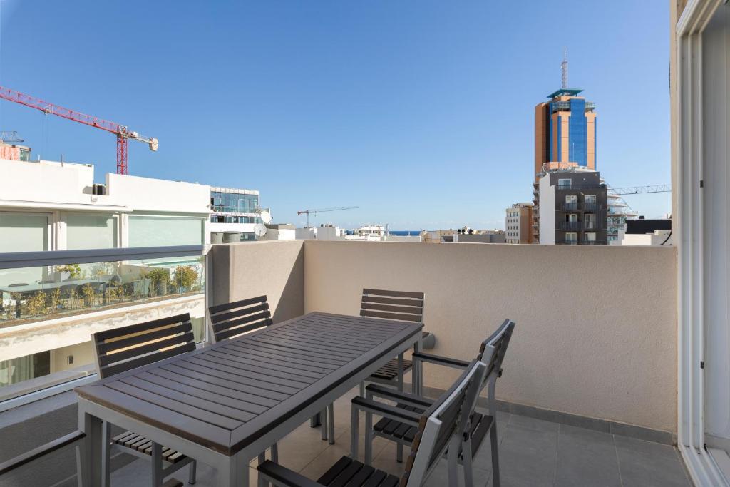 a table and chairs on a balcony with a view at Spacious & Stylish 3BR Penthouse With Large Terrace - Close to Spinola Bay in St Julian's