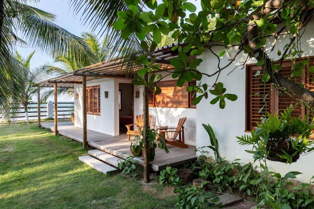 uma pequena casa branca com um alpendre em madeira em Beachfront 7-bedroom Villa in Taiba - Kitesurfing Paradise em São Gonçalo do Amarante