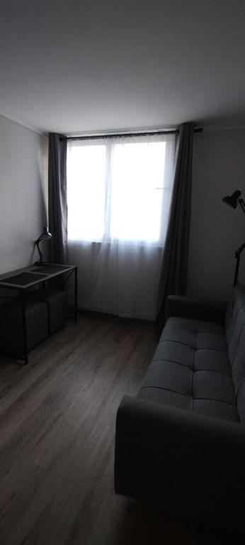 uma sala de estar com um sofá e uma grande janela em Hermoso y cómodo departamento em Santiago