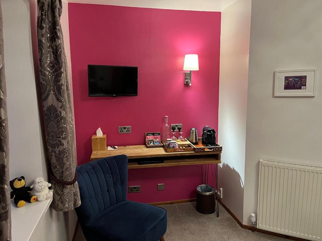 a room with a pink wall with a desk and a blue chair at Ceol na Mara Guest House in Tarbert