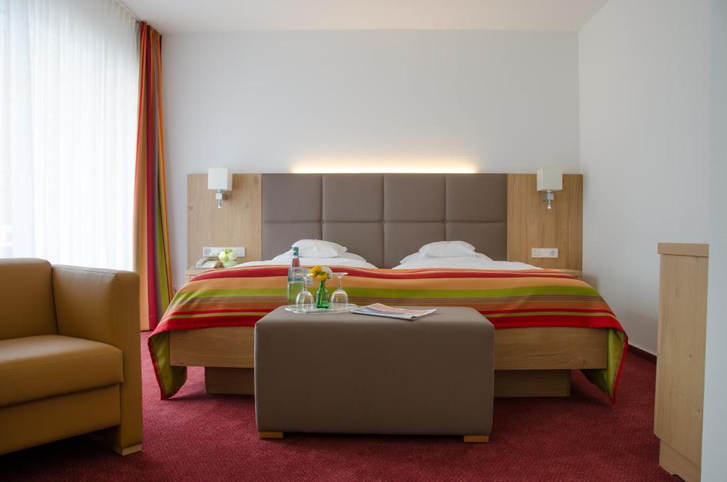 a hotel room with a bed and a chair and a table at Hotel Wieting in Oldenburg