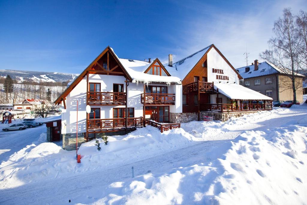 a house is covered in snow with snow at Hotel Helena in Rokytnice nad Jizerou