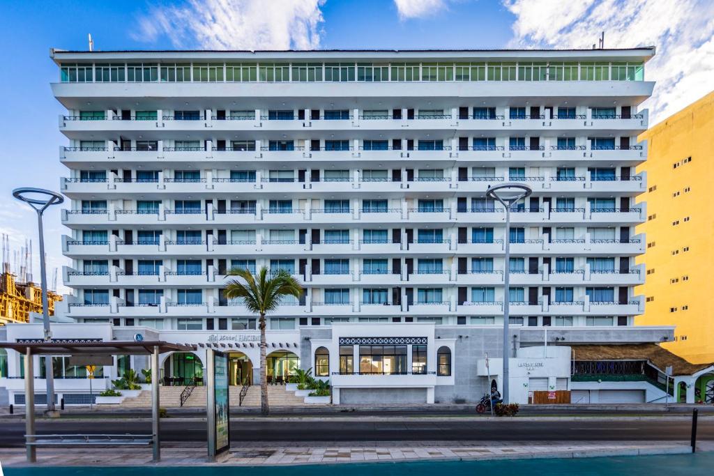 a white building with a palm tree in front of it at Hacienda Mazatlán sea view in Mazatlán