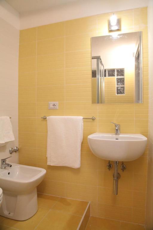 łazienka z umywalką, toaletą i lustrem w obiekcie Home Salvator Rosa 78 w mieście Neapol