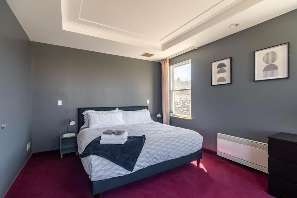 a bedroom with a large bed and a window at Urban Nest, 1-BDRM Apt in Halifax