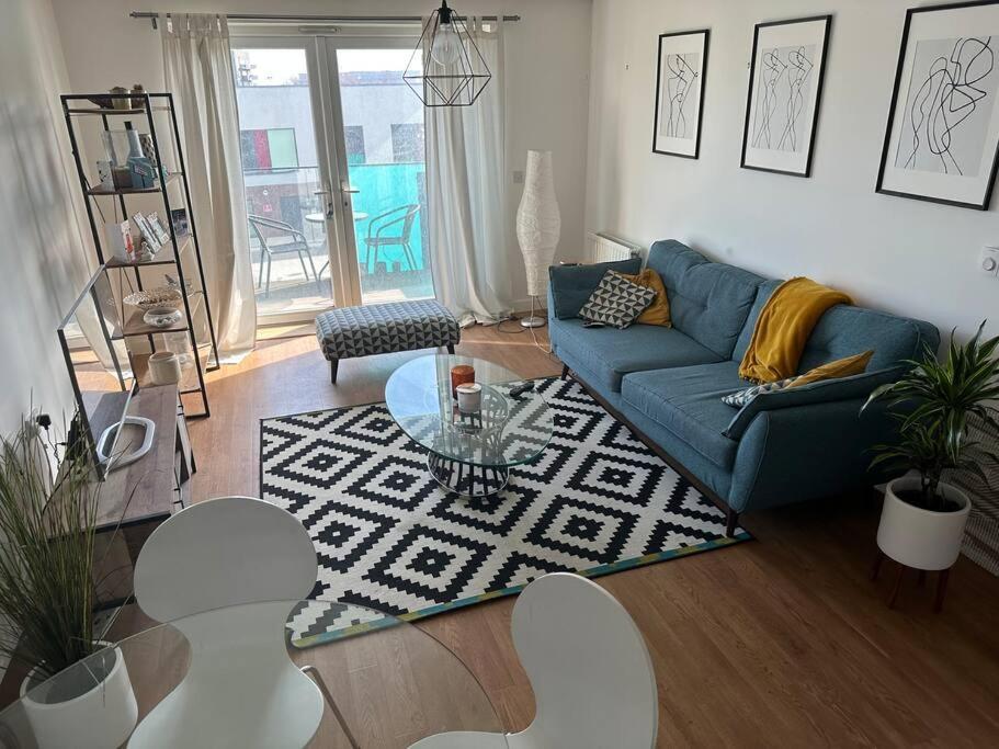 a living room with a blue couch and a table at Beautiful East London Flat in Barking