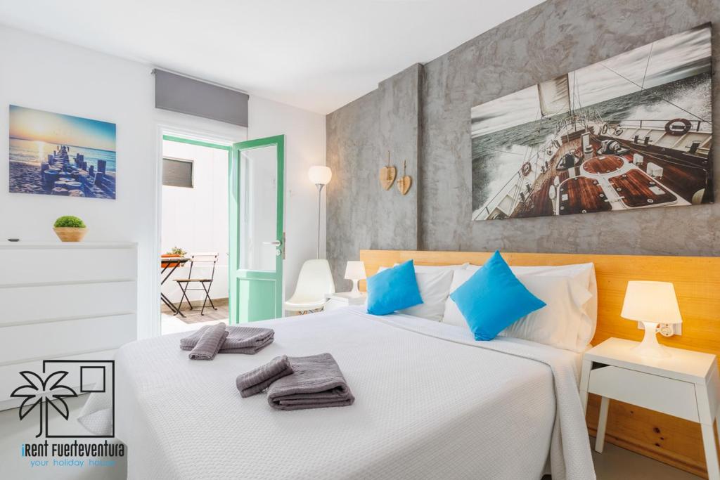a bedroom with a large white bed with blue pillows at Casa Design In the center by iRent Fuerteventura in Corralejo