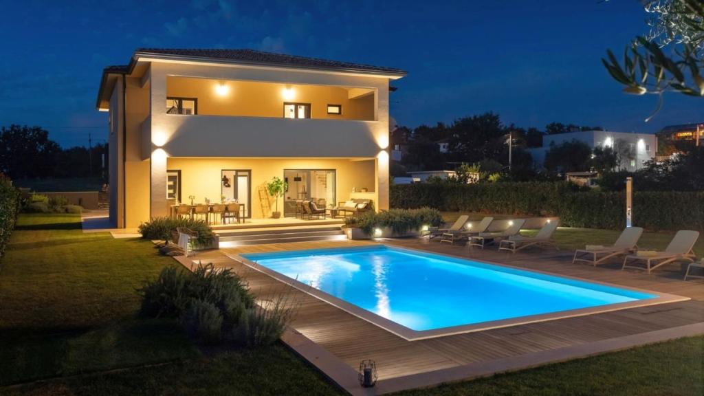 a villa with a swimming pool in front of a house at Villa Amoroso by Villas Holiday in Nova Vas