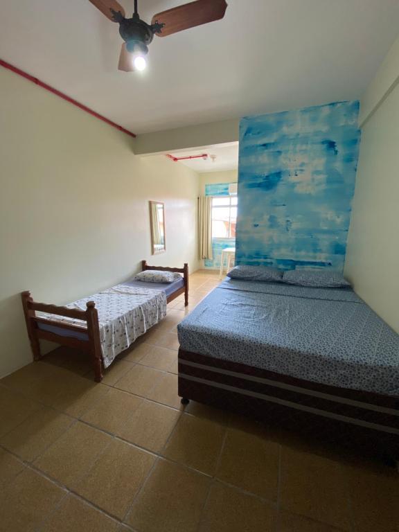 a bedroom with two beds and a ceiling fan at Pousada Vera Lucia in Guarda do Embaú