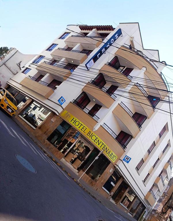 a building with a yellow sign on the front of it at Hotel Bicentenario Rionegro in Rionegro